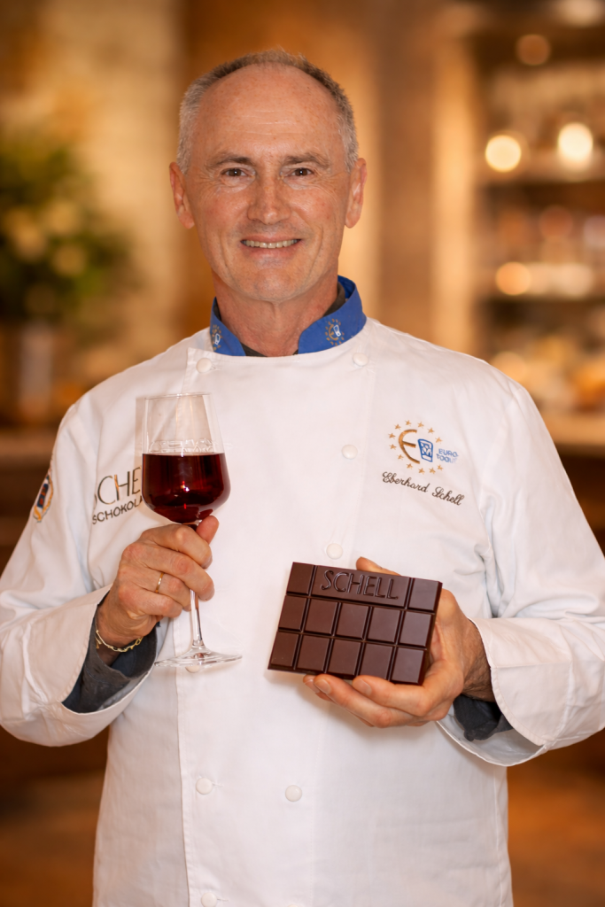 Eberhard Schell präsentiert eine dunkle Schokolade mit einem Glas Rotwein